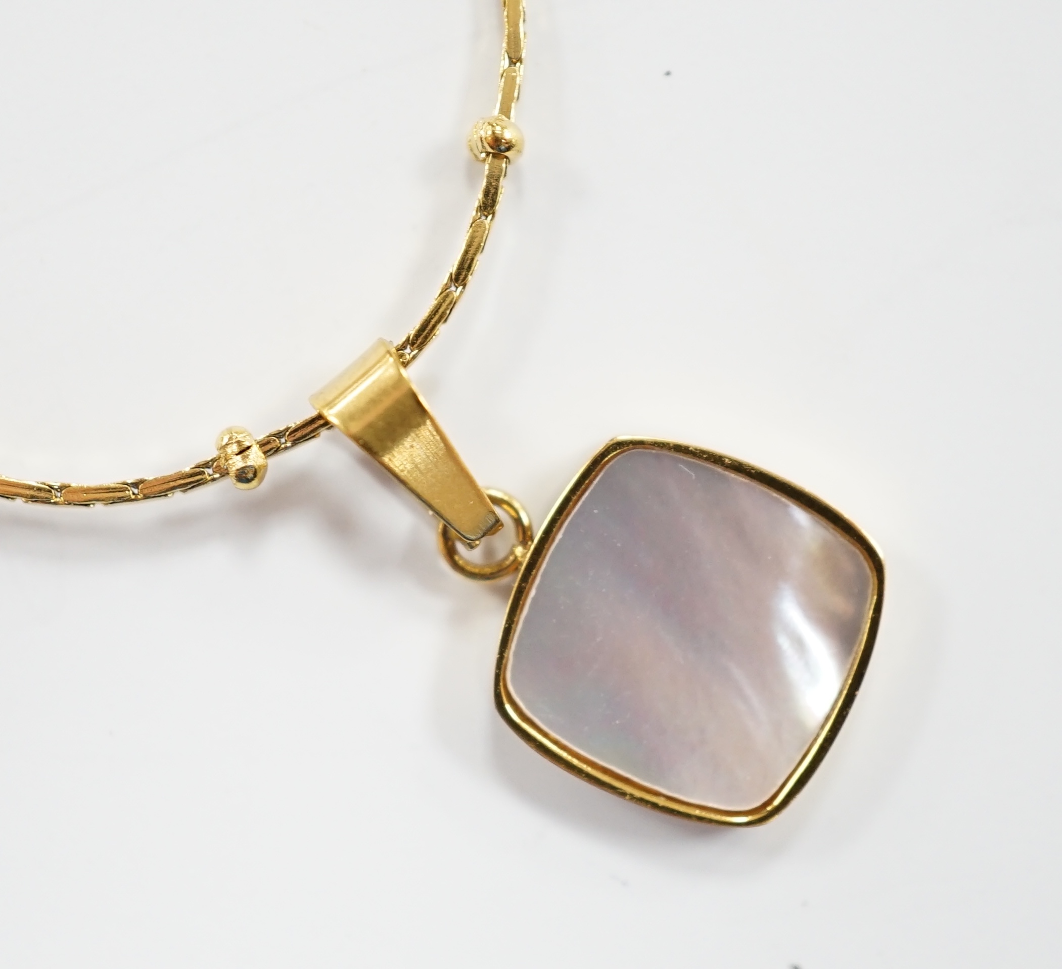 A yellow metal and mother of pearl inset pendant, 11mm on a 18kt fine link chain, 42cm, gross weight 3.4 grams.